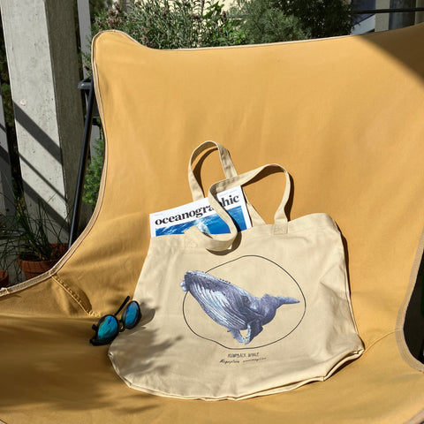 Photo of our tote bag with print of a humpback whale. Beautiful hand-drawn bag, 100% organic cotton. Here we used it as a beach bag.