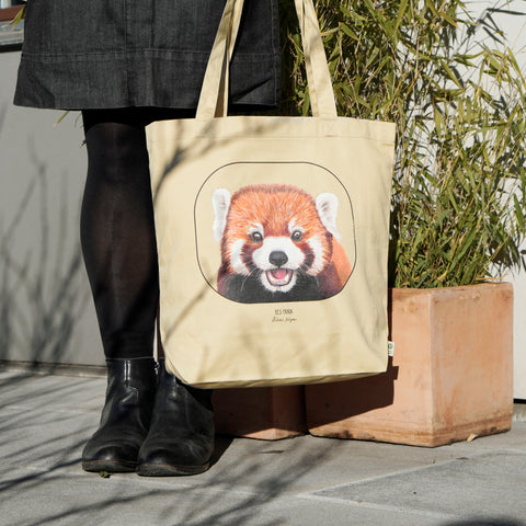 Model carrying the organic cotton tote bag with a cheeky red panda print.