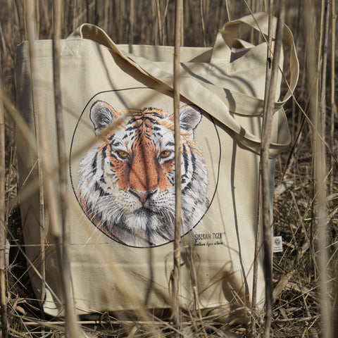 Our organic cotton tote bag with a striking siberian tiger print, hiding in a field of reeds.