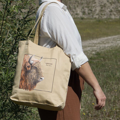 Product photo of our european bison (wisent) tote bag outside in sunlight, carried by a model.