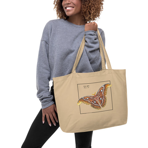Product mockup of our large organic tote bag, featuring an atlas moth. Here being held by a model.