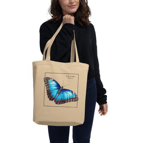 A model holding a mock up of our blue morpho tote bag. Versatile, sturdy, this bag can be used as shopping bag, gym bag or as any everyday bag!