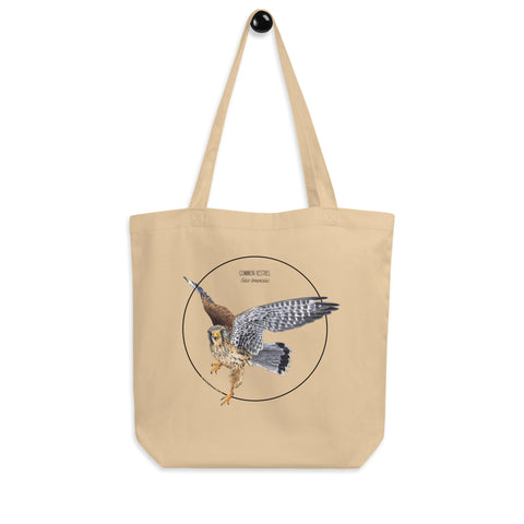 Product mockup of the organic tote bag featuring a kestrel print. Here hanging from a hanger.