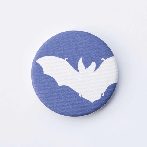 A navy-blue, fabric-covered magnet with the silhouette of a Brown Long-Eared Bat lies on a flat white surface.