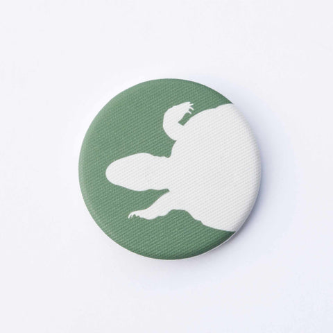 Green fabric-covered magnet with the white silhouette of a swimming turtle from above.