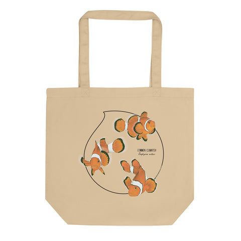 Product mockup of our organic tote bag featuring a print of 3 hand-drawn common clownfishes. Here the bag lies flat on a surface.