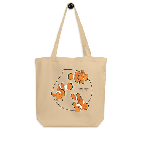 Product mockup of our organic tote bag featuring a print of 3 hand-drawn common clownfishes. Here the bag hangs from it's handles.