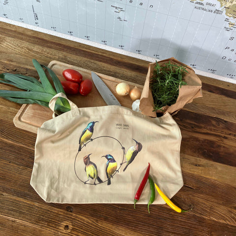 A large tote bag with a print of variable sun birds. 100% organic! Here used for grocery shopping.