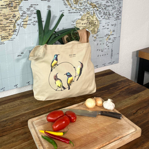 A large tote bag with a print of variable sun birds. 100% organic! Here used for grocery shopping.