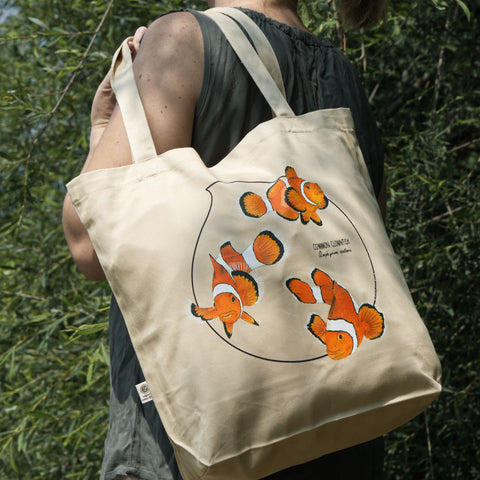Outdoor product photo of our common clownfish organic tote bag hanging over the shloulders of a model.