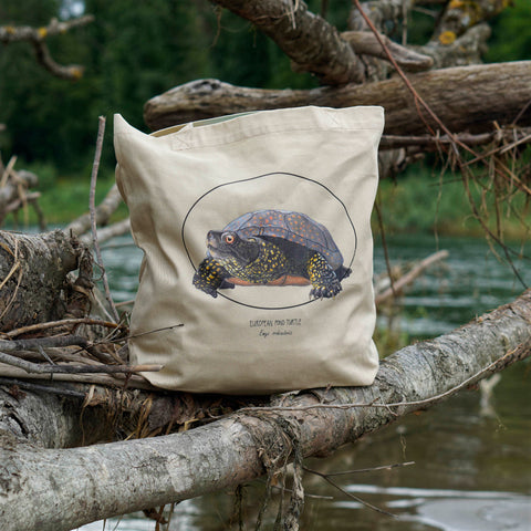 Photo of our tote bag on a model on a beach. This sturdy bag features a print of a hand-drawn European pond turtle. 100% organic cotton. Beach bag, shopping bag, travel bag, or just as a present.