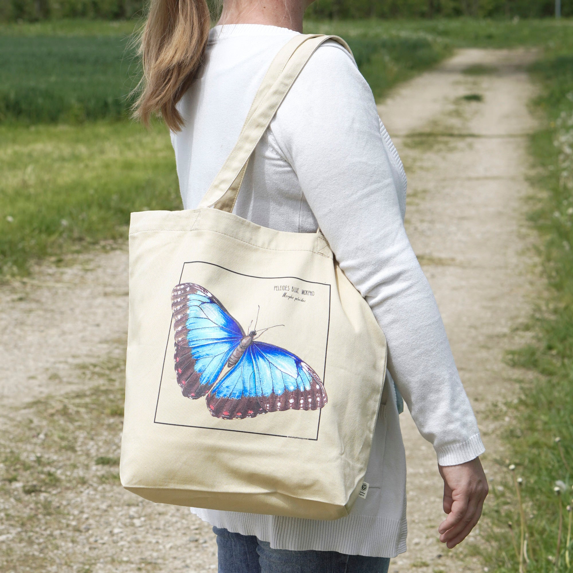 A model carrying our blue morpho tote bag in sunlight. Versatile, sturdy, this bag can be used as shopping bag, gym bag or as any everyday bag!