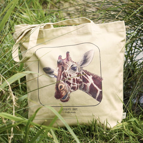 Our sturdy, spacious bag, this one shows a friendly reticulated giraffe. 100% organic cotton. Beach bag, shopping bag, library bag or just a present! Here in sunlight.