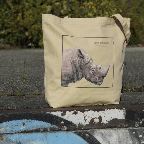 Our tote bag outside in sunlight. A beautiful, carefully drawn southern white rhinoceros is printed on the front side of the bag.