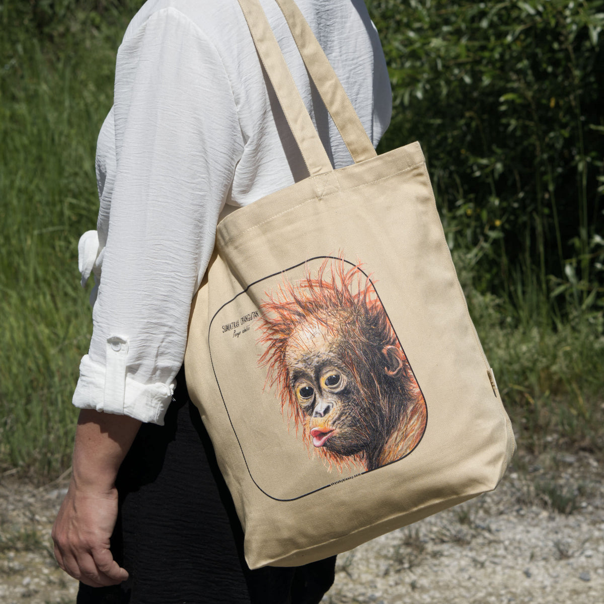 Outside product photo of the sumatran orangutan organic tote bag held over the shoulder by a model.
