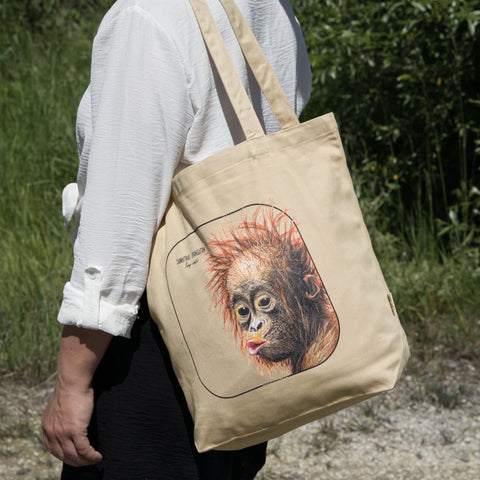 Outside product photo of the sumatran orangutan organic tote bag held over the shoulder by a model.