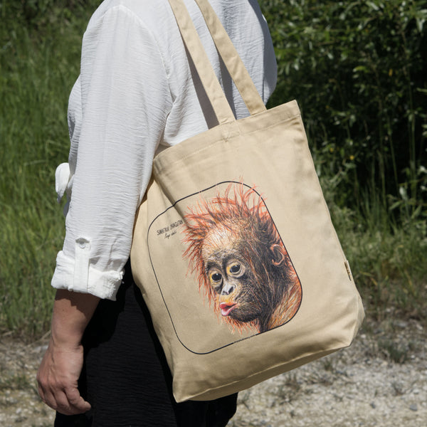 Outside product photo of the sumatran orangutan organic tote bag held over the shoulder by a model.