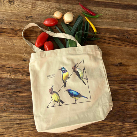 Standard size organic tote bag with a lively print of 4 variable sunbirds. Here in use with a bunch of groceries. Perfect reusable shopping bag!