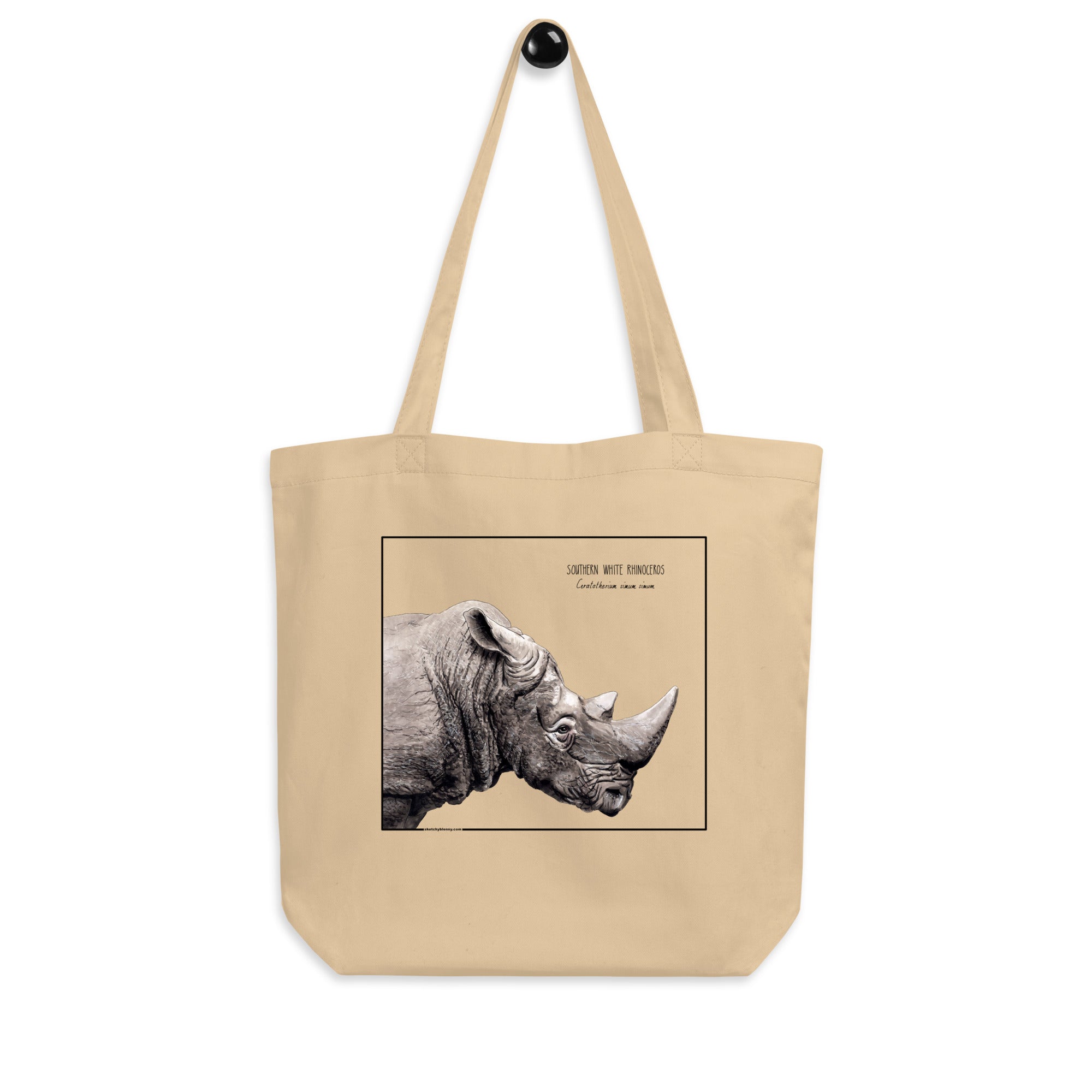 Product mockup of our tote bag with beautiful, carefully drawn southern white rhinoceros printed on the front side of the bag. Here seen hanging from a hanger.