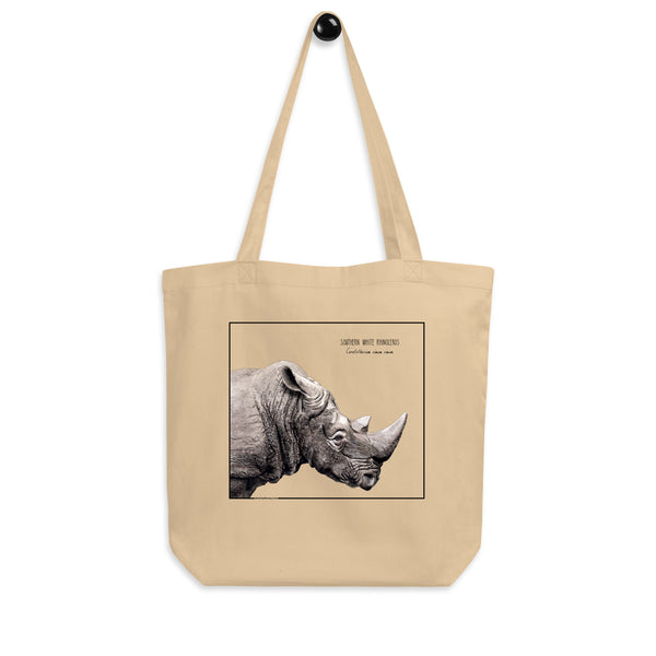 Product mockup of our tote bag with beautiful, carefully drawn southern white rhinoceros printed on the front side of the bag. Here seen hanging from a hanger.