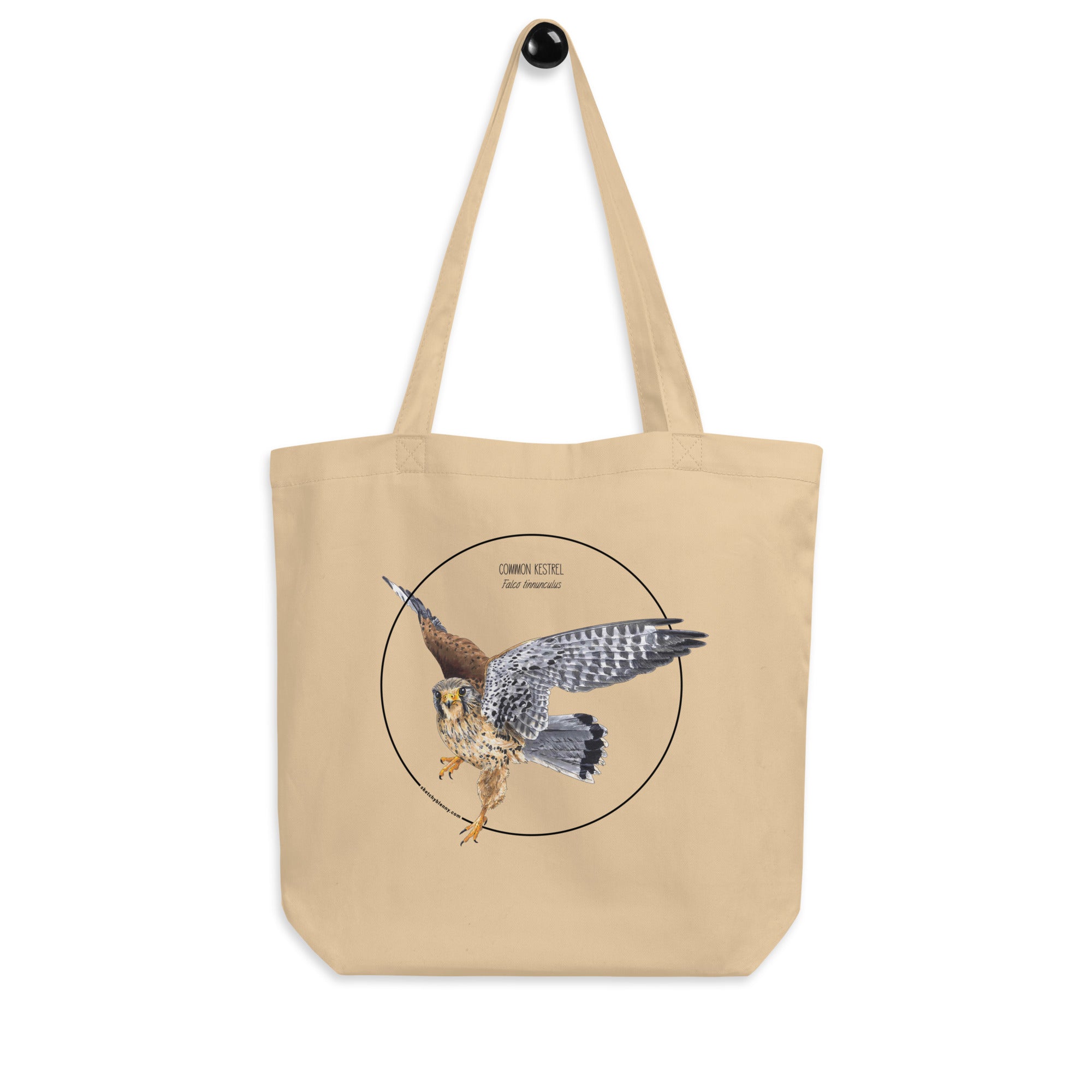 Product mockup of the organic tote bag featuring a kestrel print. Here hanging from a hanger.
