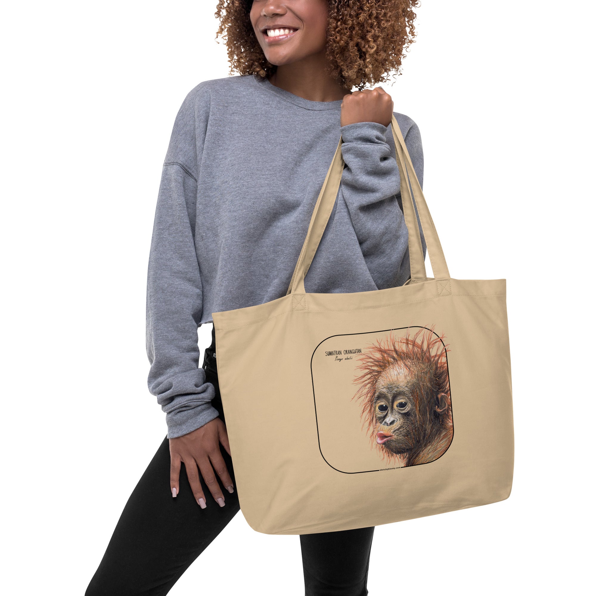 Product mockup of the large sumatran orangutan organic tote bag, here being held by a model.