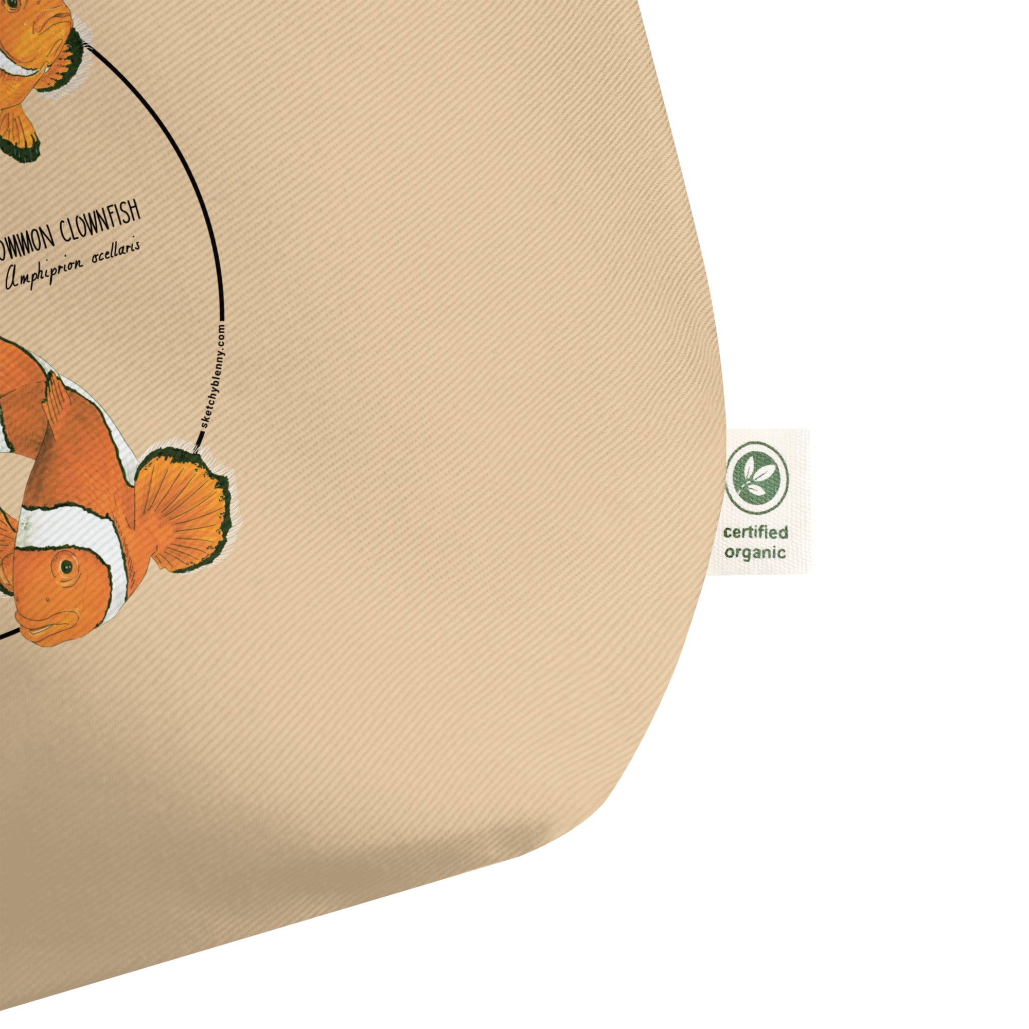 Product mockup of our large organic tote bag and a print of 3 hand-drawn common clownfishes. Here a detail of the organic label.