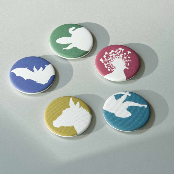 Five different coloured, fabric-covered magnets on a white surface. All feature the white silhouette of a different animal.