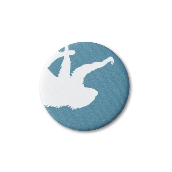 A teal-blue, fabric-covered magnet with the silhouette of a two-fingered sloth on a flat white surface. Top down photo.