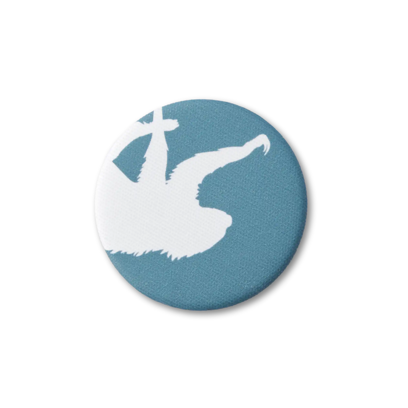 A teal-blue, fabric-covered magnet with the silhouette of a two-fingered sloth on a flat white surface. Top down photo.