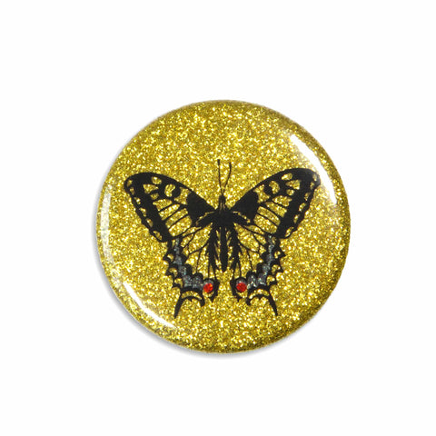 A beautiful sparkly magnet shows a swallowtail butterfly on a golden-glittery background.