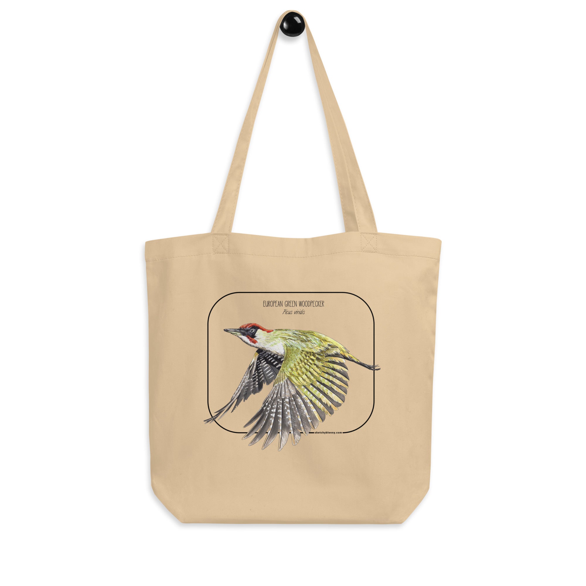 Product mockup of our 100% organic tote bag with a european green woodpecker print. Here hanging drom a wall holder.