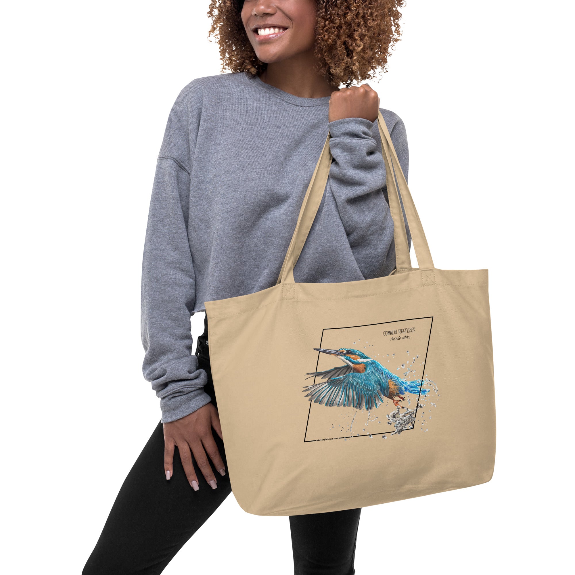 Product mockup of our large organic tote bag with a common kingfisher print. Here being held by a female model.