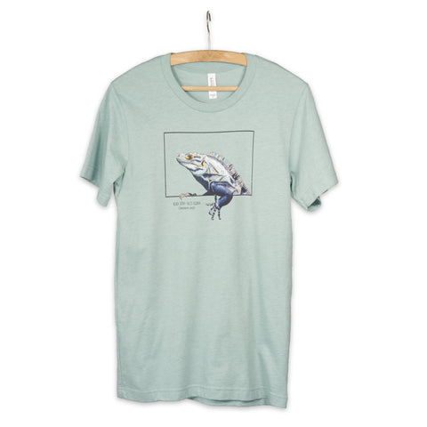 Product photo of our black iguana t-shirt on a heather prism dusty blue base colour. Hanging from a wooden hanger.