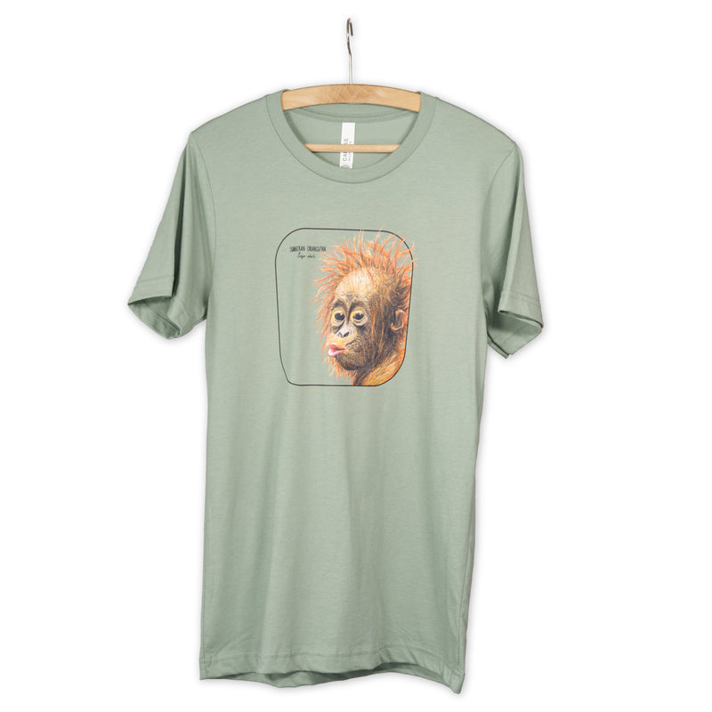Photo showing our cheeky sumatran orangutan baby smiling from a sage coloured t-shirt hanging from a wooden hanger.