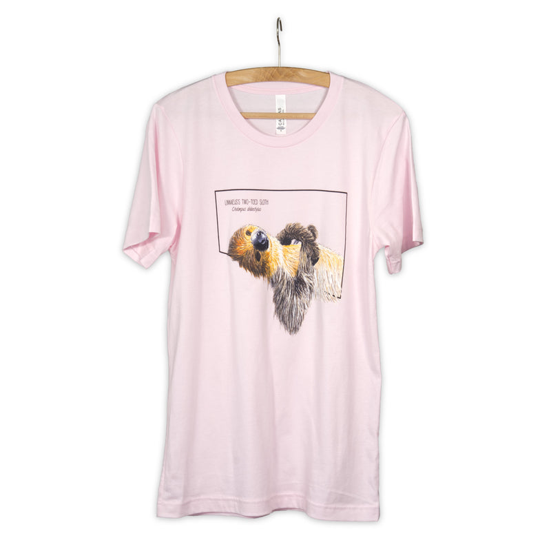 Photo showing our soft pink t-shirt with a charming two-toed sloth print on awooden hanger.